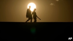 FILE - People walk along a trail at sunset, July 16, 2023, in Death Valley National Park, Calif. A new study finds the intense hot spells gripping much the American Southwest and Southern Europe could not have occurred without climate change.