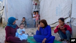 A Syrian family sits in front of their tent at a refugee camp in the town of Bar Elias, in Lebanon's Bekaa Valley, June 13, 2023. 