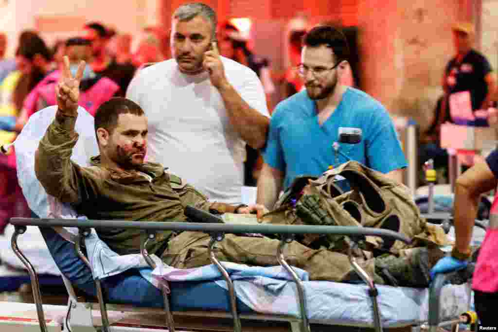 An injured Israeli officer gestures as he arrives at a hospital in Ashkelon, Israel, on Oct. 7, 2023.
