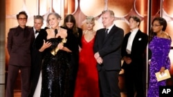 Producer Emma Thomas accepts the award for best motion picture drama for "Oppenheimer" as cast and crew members, from left, Robert Downey Jr., Matt Damon, Ludwig Göransson, Florence Pugh, Christopher Nolan, Cillian Murphy and presenter Oprah Winfrey look on. (CBS via AP)