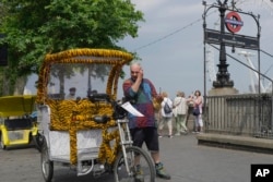 FILE - A cycle rickshaw driver wipes sweat off of his forehead during a hot day, in London, June 12, 2023.