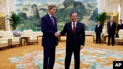U.S. Special Presidential Envoy for Climate John Kerry, left, and Chinese Premier Li Qiang shake hands before a meeting at the Great Hall of the People in Beijing, July 18, 2023. 
