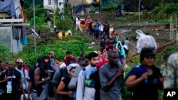 Migrants heading north line up to take a boat in Bajo Chiquito, Darien province, Panama, after walking across the Darien Gap from Colombia on Oct. 5, 2023.