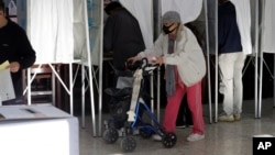 A woman emerges from a voting booth at a polling station in Taipei, Taiwan, Jan. 13, 2024. Taiwanese are casting their votes Saturday for a new president in an election that could chart the trajectory of its relations with China over the next four years.