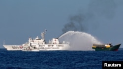 FILE - Chinese Coast Guard vessels fire water cannons towards a Philippine resupply vessel Unaizah May 4 on its way to a resupply mission at Second Thomas Shoal in the South China Sea, March 5, 2024.