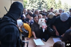 Evacuated people in the Kursk region line up to fill out forms for aid at a humanitarian distribution center in Kursk, Russia, Aug. 14, 2024.