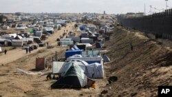 Palestinians displaced by the Israel air and ground offensive on the Gaza Striptake shelter near the border fence with Egypt in Rafah, Jan. 24, 2024. 