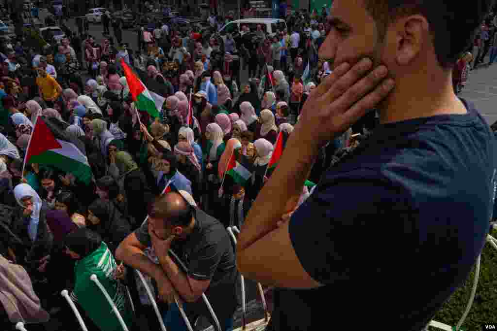 Men watch a group of women protesting against the Israeli attacks in Gaza, in the streets of Ramallah, Oct. 20, 2023. (Yan Boechat/VOA)