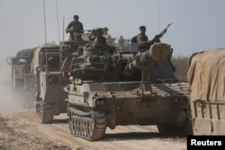 Israeli soldiers ride atop an artillery unit near the Israeli side of the border between Israel and the Gaza Strip, Nov. 3, 2023.