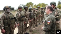 FILE - Russian Security Council Deputy Chairman Dmitry Medvedev, front right, speaks to Russian military members during his visit at a military training range in the Russian-controlled Donetsk region, Ukraine, Sept. 15, 2023. (Pool Sputnik via AP)