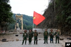 FILE - Members of the Myanmar National Democratic Alliance Army pose with the group's flag in front of the Kunlong bridge in Shan state, Myanmar, Nov. 12, 2023.