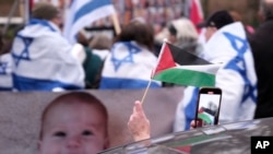 A person waves a Palestinian flag while passing a pro-Israel protest outside the International Court of Justice in The Hague, Netherlands, Jan. 12, 2024.