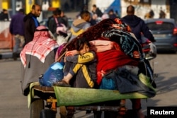 A child sits on a trailer as Palestinians flee their houses due to Israeli strikes, after a temporary truce between Hamas and Israel expired, in the eastern part of Khan Younis in the southern Gaza Strip, Dec. 1, 2023.