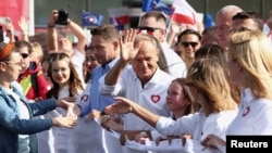 Donald Tusk, the leader of the largest opposition grouping Civic Coalition (KO), and Rafal Trzaskowski, mayor of Warsaw, stand in front of the national flag during the "Marsz Miliona Serc" rally, in Warsaw, Oct. 1, 2023.