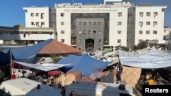 Personas, incluidos niños palestinos, que huyeron de sus casas debido a los ataques israelíes, se reúnen en el hospital Al Shifa donde se refugian, en medio del conflicto en curso entre Israel y el grupo islamista palestino Hamás, en la ciudad de Gaza el 7 de noviembre de 2023. 