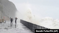 People stand on the promenade in Folkestone, England, Nov. 2, 2023, as Storm Ciaran brings high winds and heavy rain to the southern coast of England.