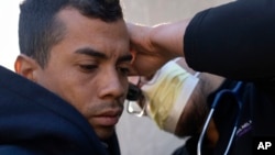 FILE - Dr. Ray Mendez, right, examines Moises Abraham Hidalgo Sarmiento, 30, of Peru outside of the 1st District police station where migrants are camped, Oct. 7, 2023, in Chicago.