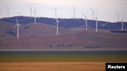 FILE - A fence is seen in front of wind turbines that are part of the Infigen Energy Capital Wind Farm located on the hills surrounding Lake George, near the Australian capital city of Canberra, Australia, Feb. 21, 2018. 