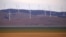 FILE - A fence is seen in front of wind turbines that are part of the Infigen Energy Capital Wind Farm located on the hills surrounding Lake George, near the Australian capital city of Canberra, Australia, Feb. 21, 2018. 