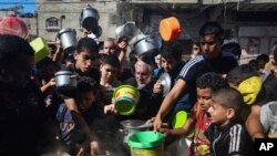 FILE - Palestinians crowd together as they wait for food distribution in Rafah, southern Gaza Strip, Nov. 8, 2023. 