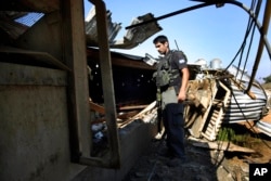 FILE - A member of Israeli security forces looks at the damage to a chicken farm from a rocket fired from Gaza Strip, July 7, 2014.