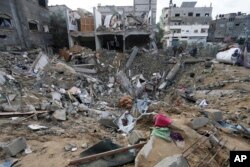 Warga Palestina melihat bangunan tempat tinggal di Deir al Balah, Jalur Gaza, yang hancur setelah serangan Israel, 14 Januari 2024. (AP/Adel Hana)