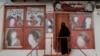 FILE - A woman wearing a niqab enters a beauty salon where the ads of women have been defaced by a shopkeeper in Kabul, Oct. 6, 2021. 
