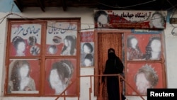 FILE - A woman wearing a niqab enters a beauty salon where the ads of women have been defaced by a shopkeeper in Kabul, Oct. 6, 2021. 