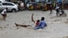 FILE - A man attempts to rescue a boy from raging floodwaters following heavy rains in Mogadishu, Somalia, Nov. 9, 2023. Farah Omar Nur, the secretary general of the Federation of Somali Journalists, says environmental journalism is not easy, especially in Somalia.