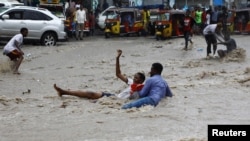 FILE - A man attempts to rescue a boy from raging floodwaters following heavy rains in Mogadishu, Somalia, Nov. 9, 2023. Farah Omar Nur, the secretary general of the Federation of Somali Journalists, says environmental journalism is not easy, especially in Somalia.