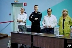 FILE - Alexei Navalny, second left, and his lawyers Alexander Fedulov, left, Olga Mikhailova, right, and Vadim Kobzev, second right, are seen on a TV screen, Vladimir region, northeast of Moscow, Aug. 4, 2023.