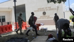 A man carries his belongings after officers of the Haitian National Police fired tear gas to clear a camp of people escaping the threat of armed gangs, in front of the US Embassy, in Port-au-Prince, Haiti, July 25, 2023.