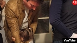 In a screengrab from video, the 3-year-old daughter of Azeri journalist Aziz Orujov hugs her father before he is arrested in November. (Kanal 13 YouTube channel)