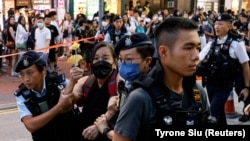 FILE - Polisi Hong Kong menahan seorang perempuan yang membawa bunga kertas di pusat kota pada peringatan 34 tahun penumpasan Lapangan Tiananmen di Beijing tahun 1989.