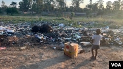 A child plays near a pile of garbage in Harare, Zimbabwe, on Jan. 17, 2024. Observers say uncollected refuse is one of the causes fueling an outbreak of cholera in Zimbabwe and other African nations. (Columbus Mavhunga/VOA)