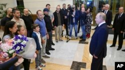 FILE - Russian President Vladimir Putin, right, speaks to released Russian prisoners upon their arrival at Vnukovo government airport outside Moscow, Aug. 1, 2024. (Kremlin pool photo via AP)