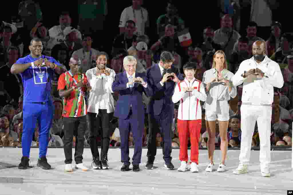 IOC President Thomas Bach, 4th-left, and President of the Paris 2024 Organizing Committee, Tony Estanguet, 5th-left, pose with athletes during the 2024 Summer Olympics closing ceremony at the Stade de France, in Saint-Denis, France, Aug. 11, 2024.