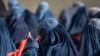 Afghan burqa-clad women sit as they wait to receive cash assistance being distributed by the World Food Program in Pul-i-Alam, the provincial capital of Logar Province, on Jan. 7, 2024. (Wakil KOHSAR / AFP)