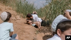 Israelis take cover as a siren sounds a warning of incoming rockets fired from the Gaza Strip in Rehovot, Israel, Oct. 13, 2023.