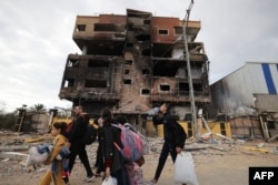 Palestinians fleeing the fighting in war-torn Gaza walk on Salaheddine road in the Zeitoun district of the southern part of the Gaza Strip, Nov. 19, 2023.