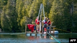 Tim Patterson, left, professor of Geology at Carleton University, leads a team of scientists as they retrieve a probe from the bottom of Crawford Lake while gathering sediment layer samples near Milton, Ontario, Canada, April 12, 2023.