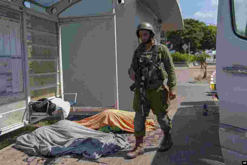 An Israeli soldier stands by the bodies of Israelis killed by Palestinian armed militants who entered from the Gaza strip, in the southern Israeli city of Sderot, on Oct. 7, 2023.