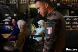 A French naval officer stands next to a wounded Palestinian child at the hospital onboard the French ship amphibious helicopter carrier Dixmude, in Al-Arish, Sinai peninsula, Egypt, Jan. 21, 2024.