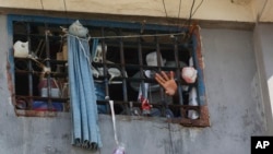 An inmate waves through a cell window at the National Penitentiary in Port-au-Prince, Haiti, Sunday, March 3, 2024. Thousands of inmates fled Haiti's main prison after armed gangs stormed the facility overnight.