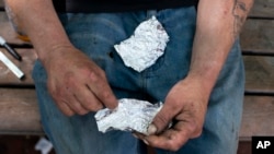 FILE - A man prepares to smoke fentanyl on a park bench in downtown Portland, Ore., May 18, 2023.