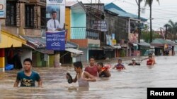 Warga wilayah Kawit di kota Cavite, selatan Manila, Filipina harus melewati jalanan yang terendam banjir akibat hujan lebat yang diperkuat oleh badai tropis Trami (19/8). 