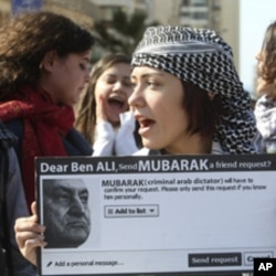 A protester carries a sign referring to ousted Tunisian President Zine al-Abidine Ben Ali and Egypt's President Hosni Mubarak during a demonstration against Mubarak in front of the Egyptian Embassy in Beirut, Feb 5, 2011
