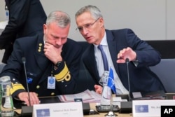 NATO Secretary-General Jens Stoltenberg, right, talks to Chair of the NATO Military Committee, Admiral Rob Bauer during a meeting of NATO defense ministers in the Ukraine Defense Contact Group format at NATO headquarters in Brussels, Oct. 12, 2022.