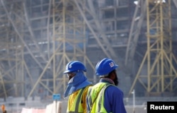 FILE - Workers walk towards the construction site of the Lusail stadium which will be build for the upcoming 2022 Fifa soccer World Cup during a stadium tour in Doha, Qatar, Dec. 20, 2019.