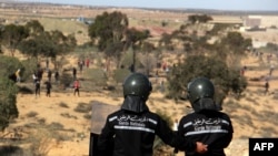 Des membres des forces de sécurité font face à des manifestants antigouvernementaux tunisiens lors d'une grève générale le 10 novembre 2021.